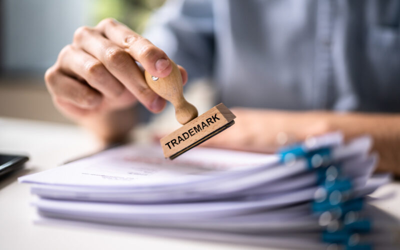 Person holding stamp that says "Trademark"