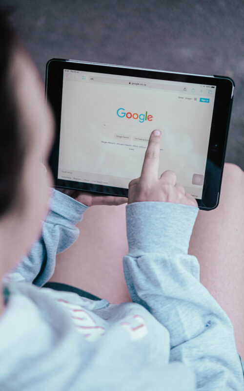 Person holding iPad and searching on Google with one finger